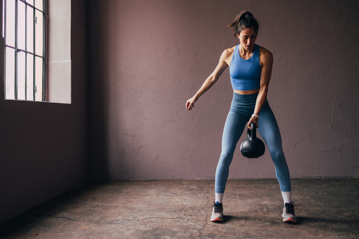 Fitness person swinging kettlebell weight.